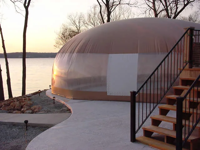 Tan pool dome enclosure beside a lake at sunset with deck stairs alongside