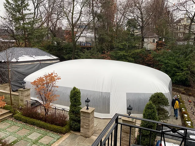White-roofed pool dome enclosure seen from a deck above with a person walking past