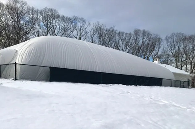 Large white pool dome enclosure in an open field after fresh snow