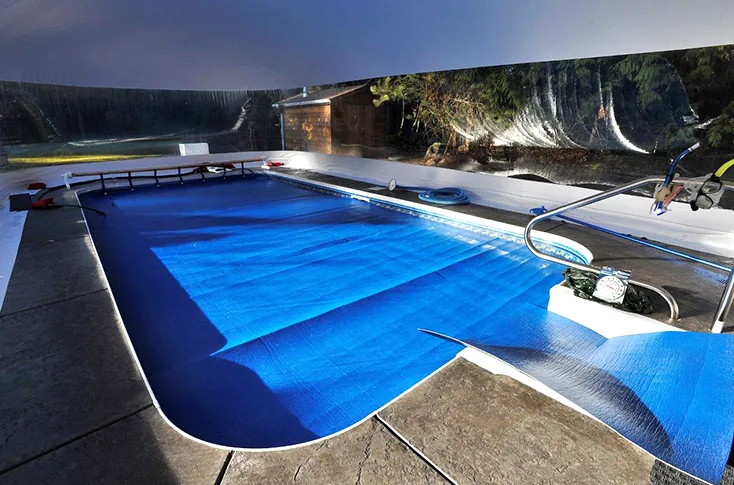 Interior of a clear-walled pool dome enclosure with the pool under a winter cover