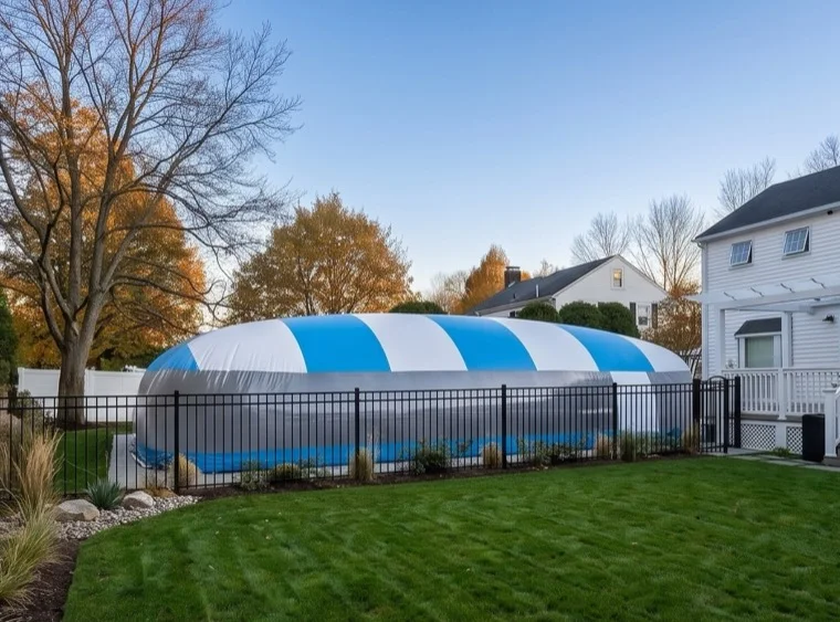 Blue and white striped pool dome enclosure in a suburban backyard in late fall