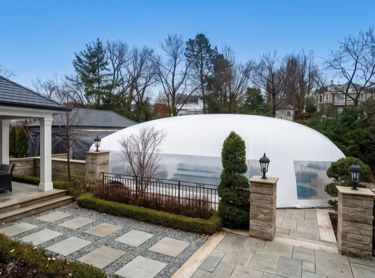 White-roofed pool dome enclosure on a landscaped property in late fall